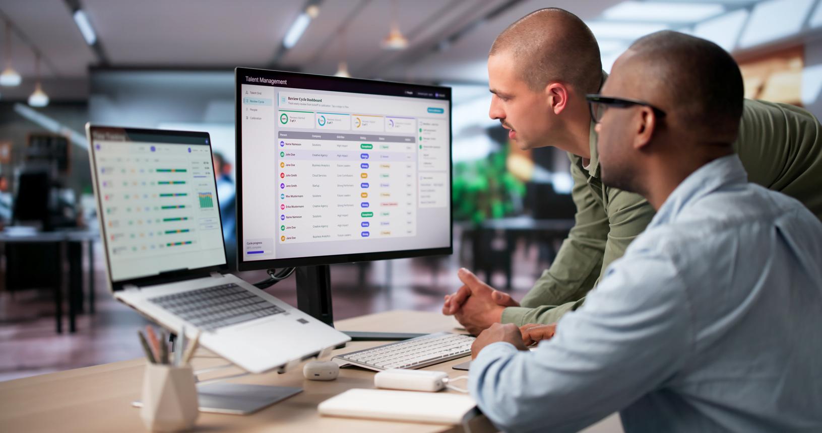 Team reviewing HR dashboard on office monitors