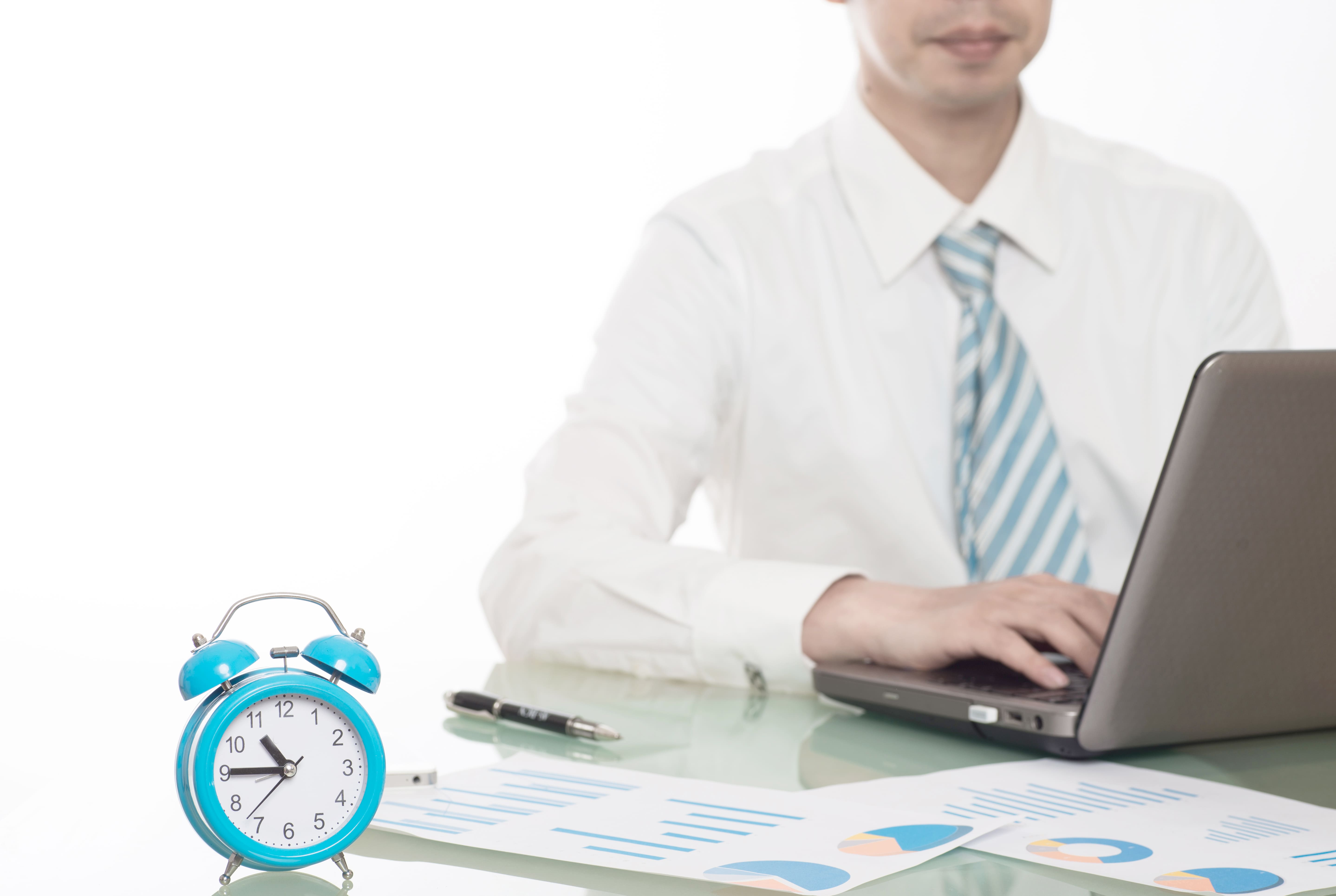 HR professional working late with time tracking reports and an office clock
